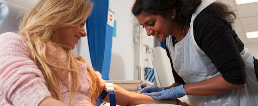 A woman takes a blood sample from a participant